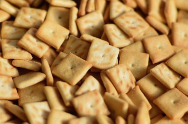 Küçük kurabiye çok kare şeklinde. Sarı tuzlu kraker bir model. Arka plan görüntüsü ile tuzlu pasta