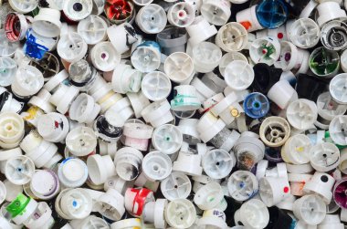 Çok sayıda grafiti sprey boya bidon kapakları. Renkli boya püskürtme uçlarını yalan büyük bir yığın ile bulaşmış