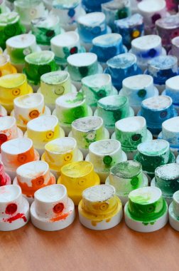Bir çok farklı renklere bulaşmış grafiti çizim için bir boya püskürtme başlıklarından bir desen. Plastik kapaklar gökkuşağı rengi oluşturan birçok satır düzenlenir