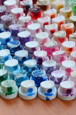 Bir çok farklı renklere bulaşmış grafiti çizim için bir boya püskürtme başlıklarından bir desen. Plastik kapaklar gökkuşağı rengi oluşturan birçok satır düzenlenir