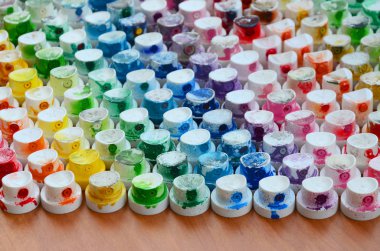 Bir çok farklı renklere bulaşmış grafiti çizim için bir boya püskürtme başlıklarından bir desen. Plastik kapaklar gökkuşağı rengi oluşturan birçok satır düzenlenir