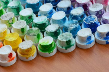 Bir çok farklı renklere bulaşmış grafiti çizim için bir boya püskürtme başlıklarından bir desen. Plastik kapaklar gökkuşağı rengi oluşturan birçok satır düzenlenir