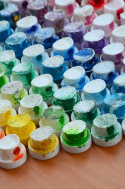 Bir çok farklı renklere bulaşmış grafiti çizim için bir boya püskürtme başlıklarından bir desen. Plastik kapaklar gökkuşağı rengi oluşturan birçok satır düzenlenir