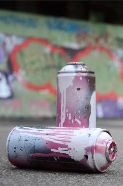 Birkaç kullanılan sprey kutular pembe ve beyaz boya ile renkli grafiti çizimlerinde boyalı duvar arka planı asfalt üzerinde yalan