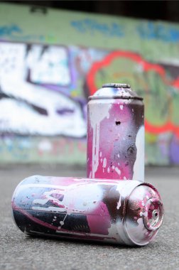 Birkaç kullanılan sprey kutular pembe ve beyaz boya ile renkli grafiti çizimlerinde boyalı duvar arka planı asfalt üzerinde yalan