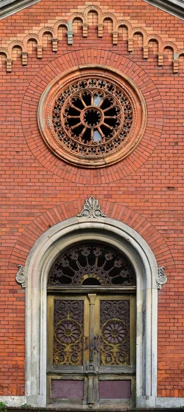 纹理前部的一个古老的砖砌体与圆形雕刻窗口和一个木门墓地 — 图库照片