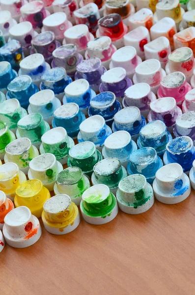 Bir çok farklı renklere bulaşmış grafiti çizim için bir boya püskürtme başlıklarından bir desen. Plastik kapaklar gökkuşağı rengi oluşturan birçok satır düzenlenir