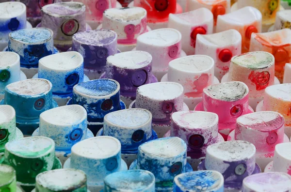 A pattern from a many nozzles from a paint sprayer for drawing graffiti, smeared into different colors. The plastic caps are arranged in many rows forming the color of the rainbow