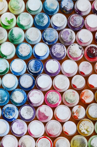 A pattern from a many nozzles from a paint sprayer for drawing graffiti, smeared into different colors. The plastic caps are arranged in many rows forming the color of the rainbow