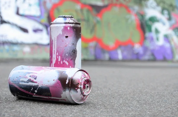 Birkaç kullanılan sprey kutular pembe ve beyaz boya ile renkli grafiti çizimlerinde boyalı duvar arka planı asfalt üzerinde yalan