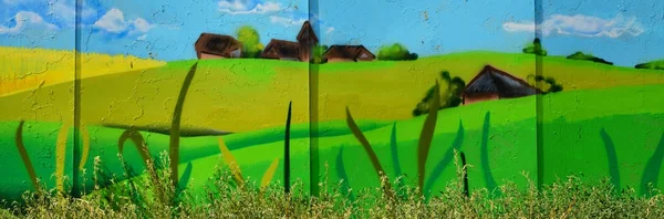 The old wall, painted in color graffiti drawing with aerosol paints. An image of a traditional Ukrainian landscape with sunflowers, kalina and a mill in a field