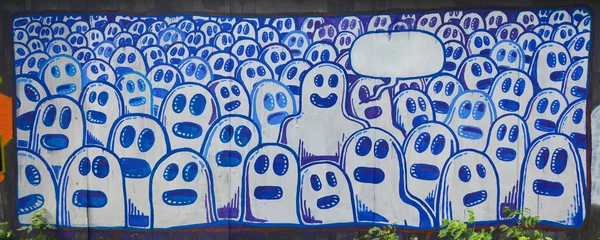 The old wall, painted in color graffiti drawing with aerosol paints. The image of a set of identical cartoon faces as concept of senseless crowd with one outstanding character and a cloud for speech