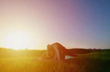 İki genç sarışın kız spor pratik yoga açık havada pitoresk bir yeşil tepenin üzerinde akşam uygun. Açık havada spor egzersiz kavramı