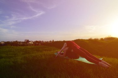 İki genç sarışın kız spor pratik yoga açık havada pitoresk bir yeşil tepenin üzerinde akşam uygun. Açık havada spor egzersiz kavramı