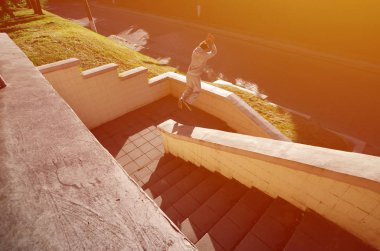 Genç bir adam uzayda atlama beton korkuluk arasında gerçekleştirir. Sokak koşullarda eğitim atlet uygulamaları parkour. Spor altkültürler gençler arasında kavramı