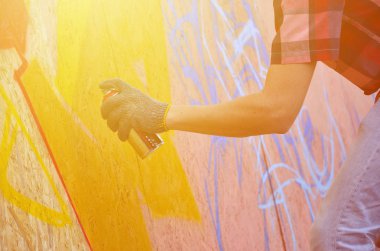 Bir el bir sprey ile yeni bir grafiti duvara çekiyor olabilir. Bir ahşap duvar yakın çekim bir grafiti çizim işlemi fotoğrafı. Sokak sanatı ve yasadışı vandalizm kavramı