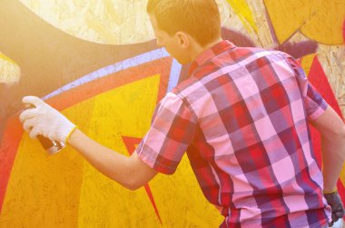 Bir genç Kızıl saçlı grafiti sanatçısı yeni bir graffiti duvar boyar. Bir duvara yakın çekim bir grafiti çizim işlemi fotoğrafı. Sokak sanatı ve yasadışı vandalizm kavramı