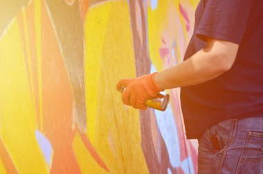 Bir el bir sprey ile yeni bir grafiti duvara çekiyor olabilir. Bir ahşap duvar yakın çekim bir grafiti çizim işlemi fotoğrafı. Sokak sanatı ve yasadışı vandalizm kavramı