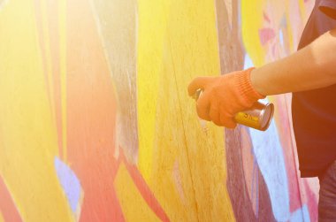 Bir el bir sprey ile yeni bir grafiti duvara çekiyor olabilir. Bir ahşap duvar yakın çekim bir grafiti çizim işlemi fotoğrafı. Sokak sanatı ve yasadışı vandalizm kavramı