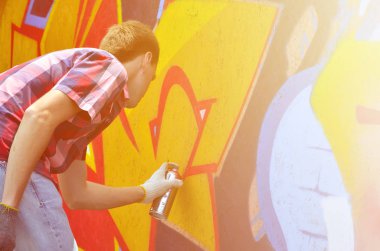 Bir genç Kızıl saçlı grafiti sanatçısı yeni bir graffiti duvar boyar. Bir duvara yakın çekim bir grafiti çizim işlemi fotoğrafı. Sokak sanatı ve yasadışı vandalizm kavramı