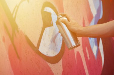 Bir el bir sprey ile yeni bir grafiti duvara çekiyor olabilir. Bir ahşap duvar yakın çekim bir grafiti çizim işlemi fotoğrafı. Sokak sanatı ve yasadışı vandalizm kavramı