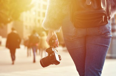 Bir kadın fotoğrafçı ile birçok kişi ile kalabalık Caddesi'nin arka plan bulanık karşı onun elinde siyah bir modern dijital photocamera arkadan görünüş