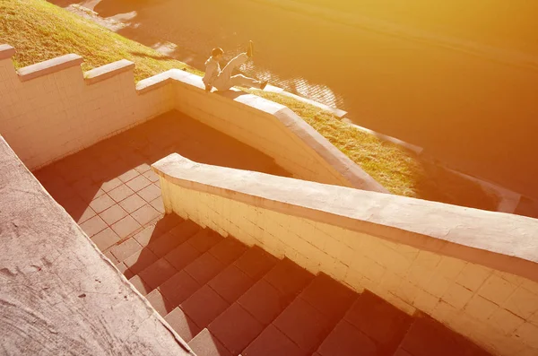 A young guy performs a jump through the concrete parapet. The athlete practices parkour, training in street conditions. The concept of sports subcultures among youth