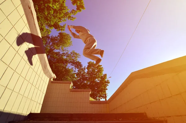 A young guy performs a jump through the space between the concrete parapets. The athlete practices parkour, training in street conditions. Bottom view