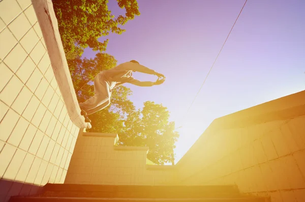 A young guy performs a jump through the space between the concrete parapets. The athlete practices parkour, training in street conditions. Bottom view