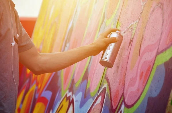 Bir genç Kızıl saçlı grafiti sanatçısı yeni bir graffiti duvar boyar. Bir duvara yakın çekim bir grafiti çizim işlemi fotoğrafı. Sokak sanatı ve yasadışı vandalizm kavramı