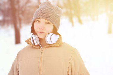 Oldukça çekici beyaz gözlü kız hipster kış park portresi. Kulaklıklar üzerinde müzik dinliyor. Gençlik sokak moda. Kış eğlence.