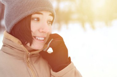Oldukça çekici beyaz gözlü kız hipster kış Park portresi. Modern smartphone konuşuyor. Gençlik sokak moda. Kış eğlence. Açık havada yürüyüşler.