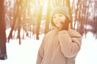 Oldukça çekici beyaz gözlü kız hipster kış Park portresi. Modern smartphone konuşuyor. Gençlik sokak moda. Kış eğlence. Açık havada yürüyüşler.