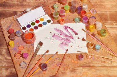 Arka plan resmi suluboya resim ve sanat ilgi gösteriliyor. Boyalı bir parça kağıt, fırçalar, bir eski ve lekeli ahşap yüzeye yalan suluboya boya ve guaş, kavanoz çevrili