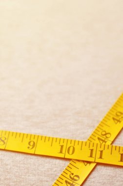 Cm veya inç şeklinde sayısal göstergeler ile sarı renk ölçüm bandı üzerinde gri bir örme kumaş yatıyor. Arka plan görüntüsü dikiş kıyafetler, insanlar için hakkında kim zayıflama