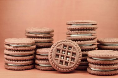 Çikolatalı sandviç bisküvi vanilya krema boşaltmak kahverengi ahşap tablo doldurma ile yuvarlak. Natürmort beyaz krema dolgulu tatlı ve lezzetli Kurabiye.