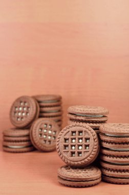 Çikolatalı kurabiye yığını ahşap kahverengi yüzeyi vanilya beyaz krem yalanlarla dolu. Tatlı ve lezzetli sandviç bisküvi yuvarlak. Detaylı gıda fotoğrafçılığı ile boşaltmak