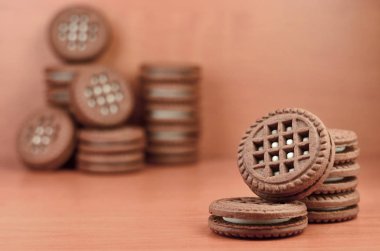 Çikolatalı sandviç bisküvi vanilya krema boşaltmak kahverengi ahşap tablo doldurma ile yuvarlak. Natürmort beyaz krema dolgulu tatlı ve lezzetli Kurabiye.