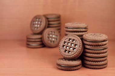 Çikolatalı sandviç bisküvi vanilya krema boşaltmak kahverengi ahşap tablo doldurma ile yuvarlak. Natürmort beyaz krema dolgulu tatlı ve lezzetli Kurabiye.