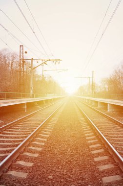 Bir tren istasyonu trenler güneşli bir günde bir çok ağaçlar ve tarlaları arasında bir kentsel yerleşim için beklediğiniz platformları ile. Demiryolu erken Bahar sezonu