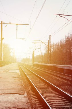 Bir tren istasyonu trenler güneşli bir günde bir çok ağaçlar ve tarlaları arasında bir kentsel yerleşim için beklediğiniz platformları ile. Demiryolu erken Bahar sezonu