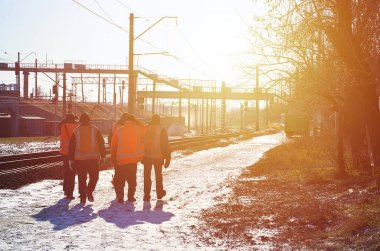 Kirli turuncu üniformaları işaret içinde birkaç demiryolu işçileri yolun demiryolu hattı yanında bulunmaktadır. Tren mürettebat kış güneşli sabah işe gider.