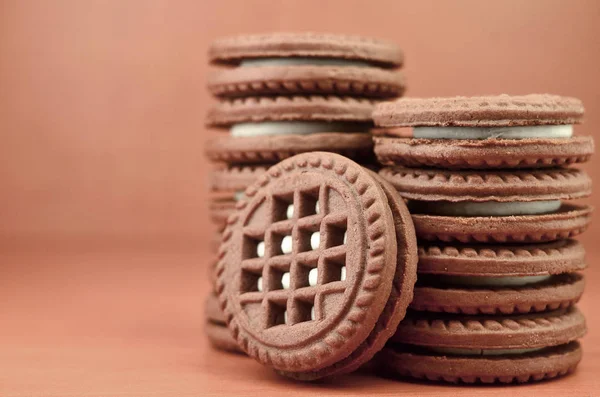 Çikolatalı kurabiye yığını ahşap kahverengi yüzeyi vanilya beyaz krem yalanlarla dolu. Tatlı ve lezzetli sandviç bisküvi yuvarlak. Detaylı gıda fotoğrafçılığı ile boşaltmak