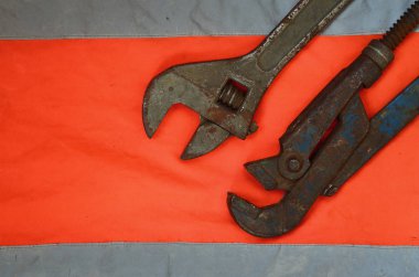 Ayarlanabilir ve boru anahtarı bir turuncu sinyal işçi gömlek arka planı. Natürmort onarım, tren veya sıhhi tesisat işleri ile ilgili