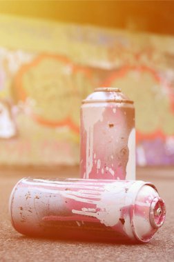 Birkaç kullanılan sprey kutular pembe ve beyaz boya ile renkli grafiti çizimlerinde boyalı duvar arka planı asfalt üzerinde yalan