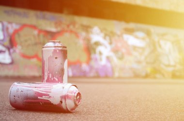 Birkaç kullanılan sprey kutular pembe ve beyaz boya ile renkli grafiti çizimlerinde boyalı duvar arka planı asfalt üzerinde yalan