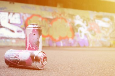 Birkaç kullanılan sprey kutular pembe ve beyaz boya ile renkli grafiti çizimlerinde boyalı duvar arka planı asfalt üzerinde yalan