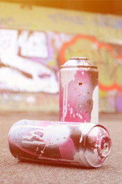Birkaç kullanılan sprey kutular pembe ve beyaz boya ile renkli grafiti çizimlerinde boyalı duvar arka planı asfalt üzerinde yalan