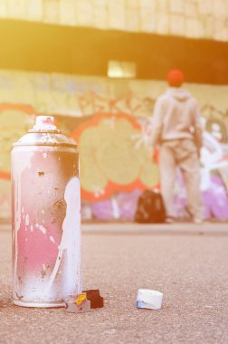 Pembe ve beyaz boya yalan üzerine boyalı duvar grafiti çizimlerinde önünde duran adam asfaltta kullanılan sprey boya sprey olabilir