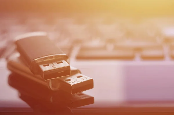 USB flash cards lying on black laptop case in front of his keyboard. Virtual memory storage with USB output